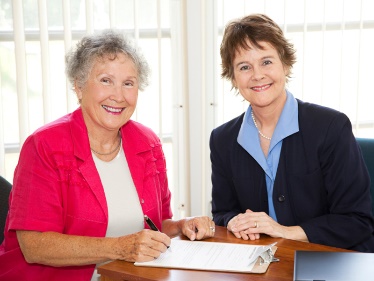 Two people smiling, with a document between them. 