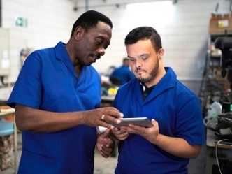 Two men in working uniforms reading an iPad.