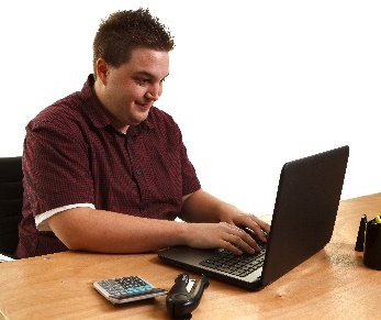 A person smiling, using a laptop. 