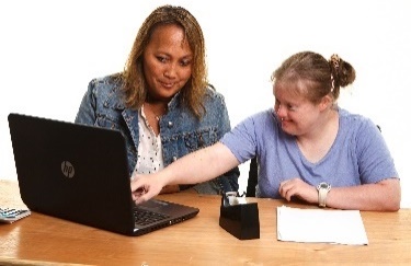 A person with disability pointing to a laptop screen, showing someone else what they think. 