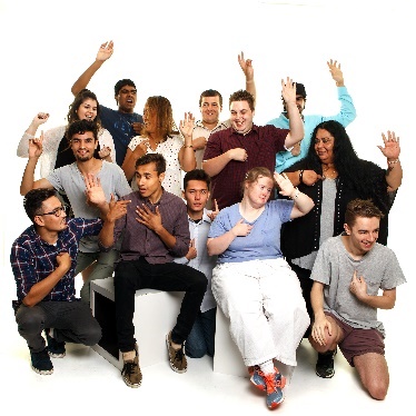 A group of people pointing at themselves with their hands raised. 