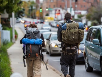 Two people with backpacks walking down a street.