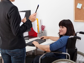 A woman in a wheelchair working in an office.