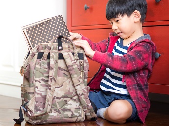 A child packing a school bag. 