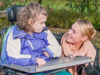 A woman talking to a girl in a wheelchair. 