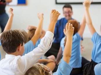 A group of students raising their hand in class.