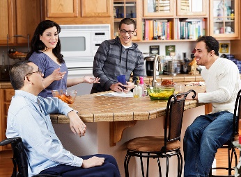 A group of people sitting and standing in a kitchen. 