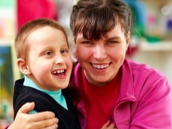 A woman hugging a young boy with disability. 